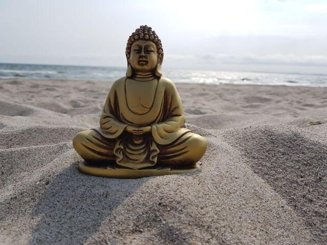 Goldener Buddha am Strand mit Meer im Hintergrund